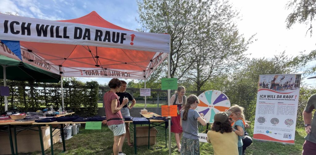 Menschen vor einem Infostand mit einem Glücksrad