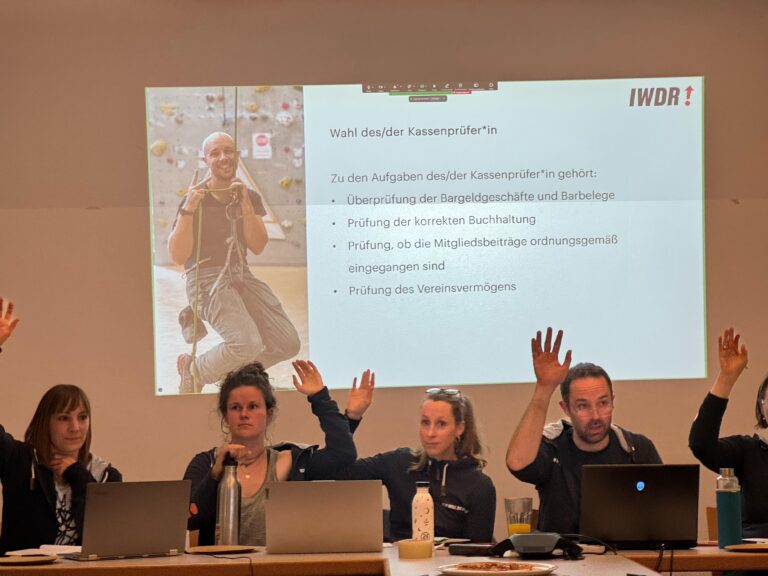 Mitgliederversammlung Abstimmung bei der Mitgliederversammlung des IWDR. Verschiedene Personen der Geschäftsstelle heben ihre Hand.